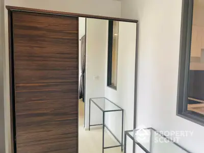 Modern interior with sleek wooden sliding door and glass table in a stylish apartment.