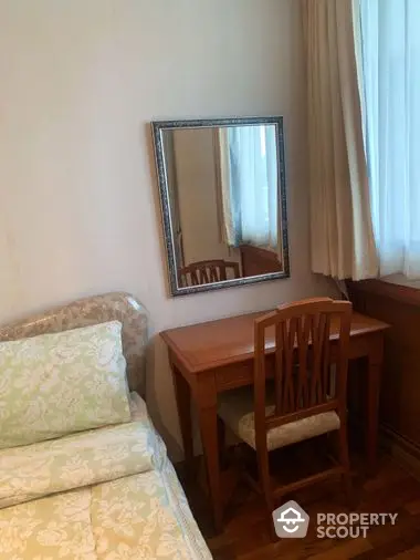 Cozy and inviting bedroom with classic wooden furniture, a comfortable single bed, and a large mirror reflecting natural light from the window.