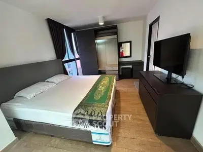 Spacious bedroom with modern furnishings and large window for natural light.