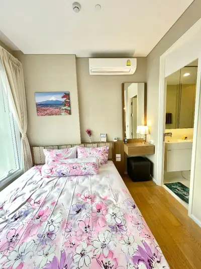 Charming bedroom with floral bedding and ensuite bathroom in modern apartment