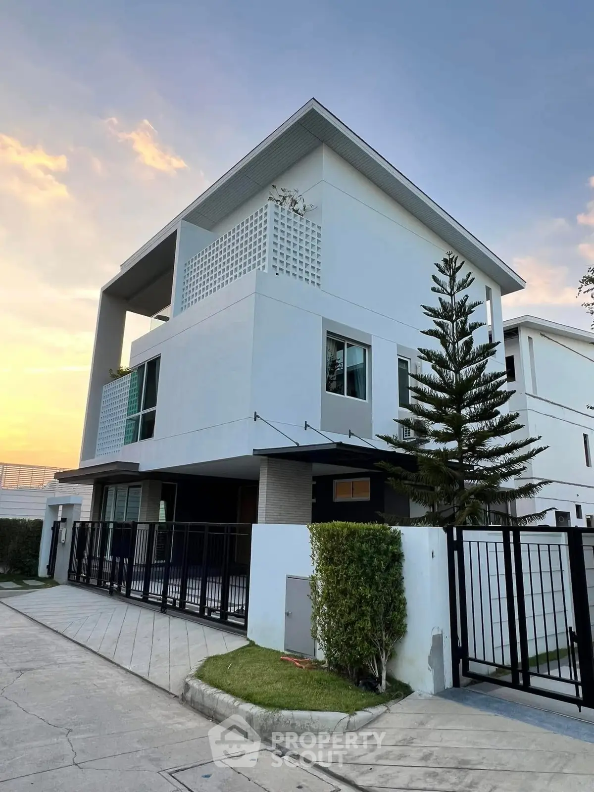 Modern three-story house with sleek design and spacious balcony at sunset