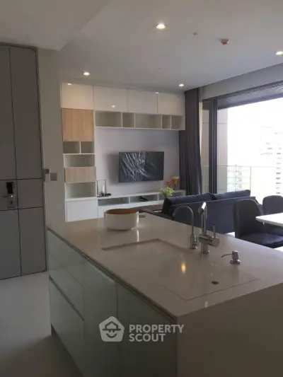 Modern open-plan living room with sleek kitchen island and large balcony view.