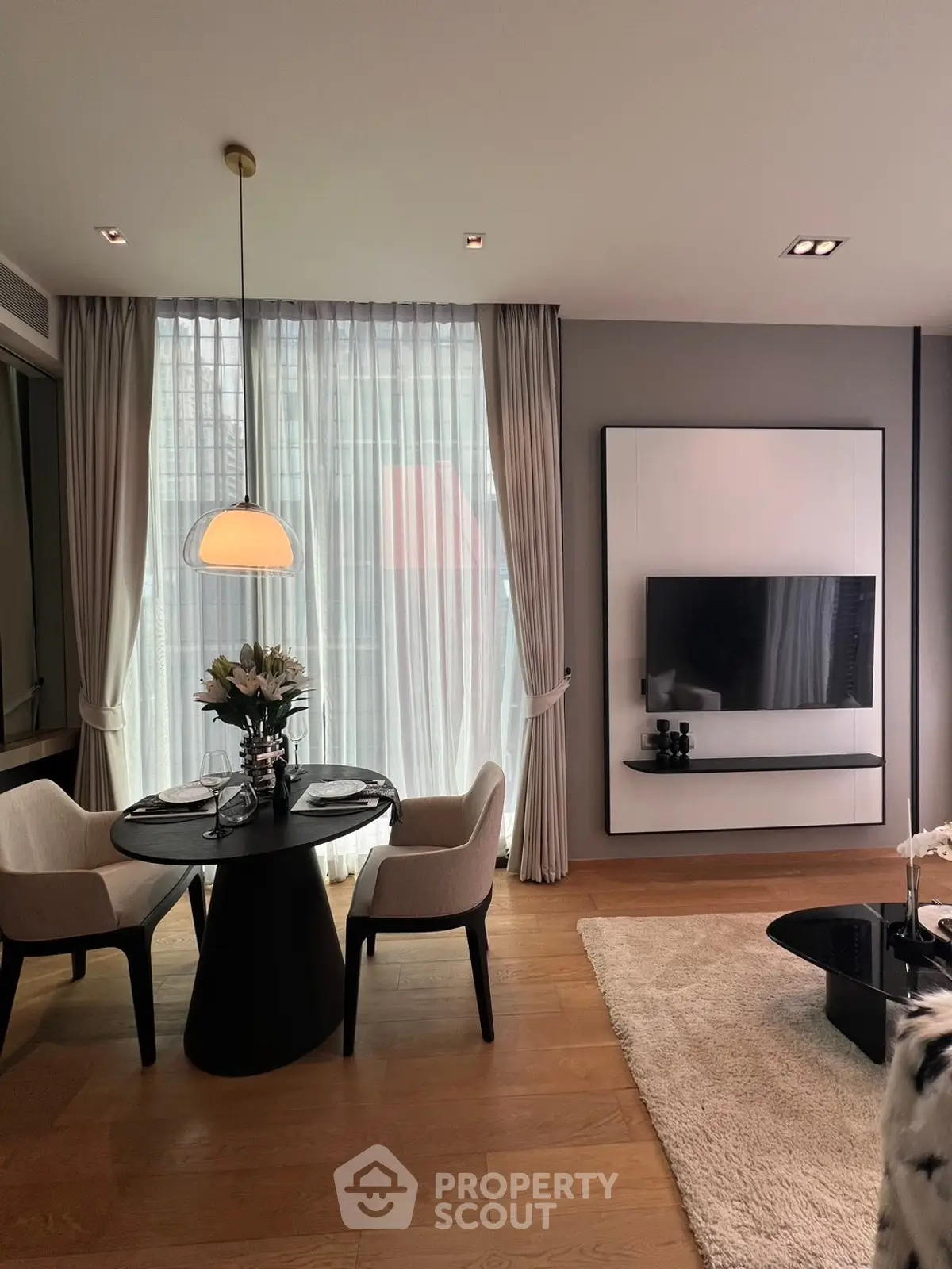 Elegant modern living room with dining area, stylish decor, and natural light through large windows.