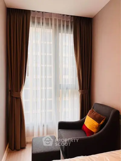 Cozy bedroom corner with armchair and large window, perfect for relaxation.