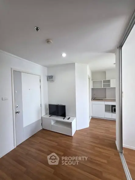 Modern apartment interior with open layout and wooden flooring, featuring a compact kitchen and living area.