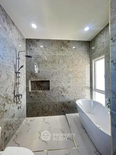 Luxurious marble bathroom with freestanding bathtub and modern shower fixtures.