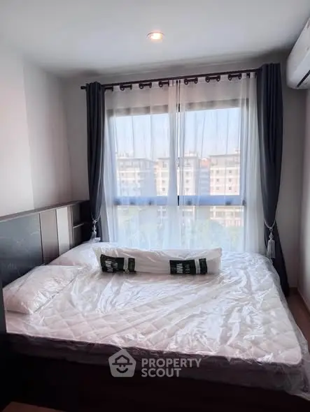 Cozy bedroom with large window and modern decor in urban apartment.