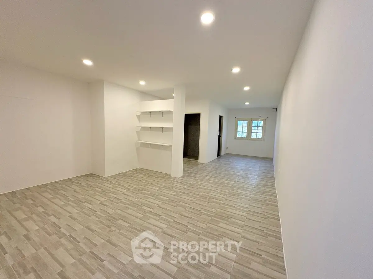 Spacious open-plan living area with modern flooring and built-in shelves, perfect for customization.