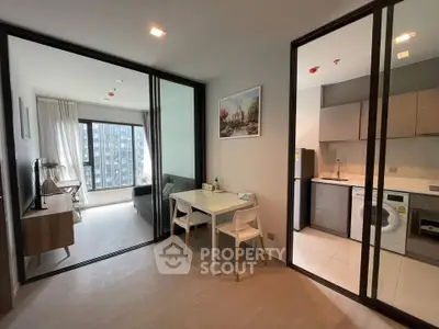 Modern apartment interior with open kitchen and living area, featuring sleek furniture and large windows.