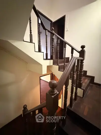 Elegant wooden staircase with classic balustrades in a well-lit interior space.