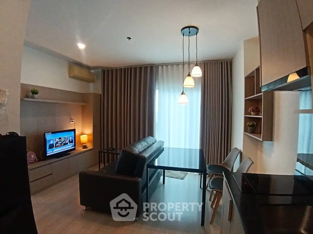 Modern living room with cozy sofa, TV, and stylish lighting in open layout apartment.