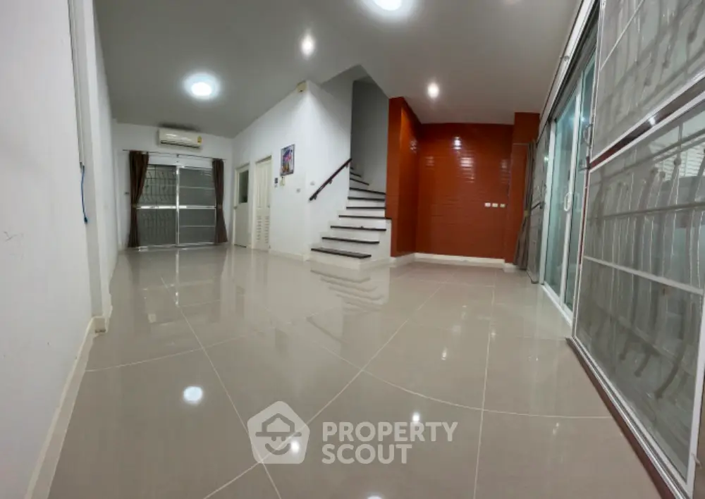 Spacious modern living room with sleek tile flooring and staircase