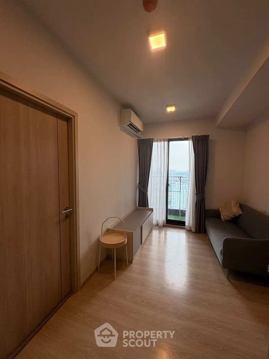 Cozy living room with balcony view, featuring modern sofa and air conditioning.