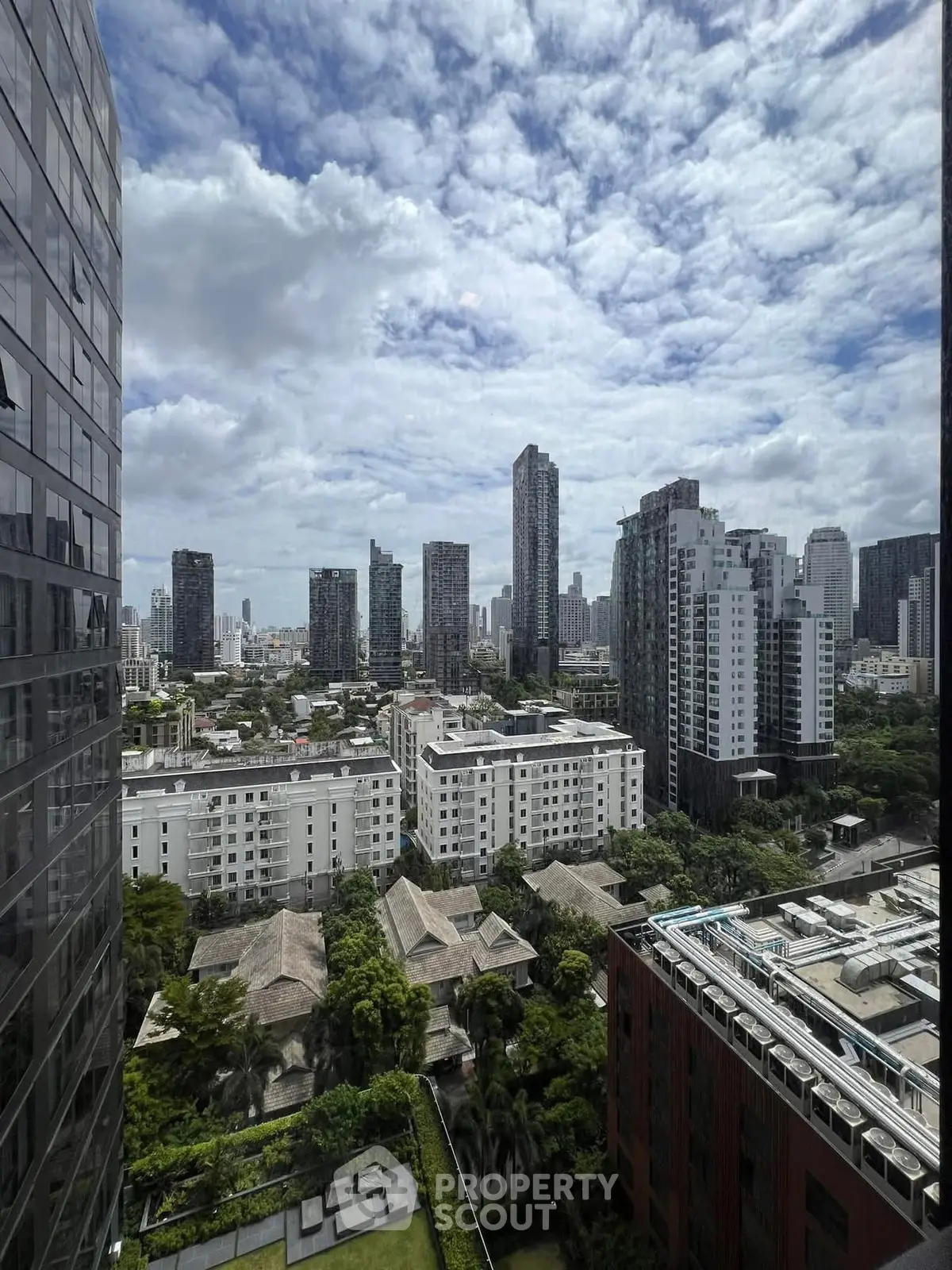 Stunning cityscape view from high-rise building showcasing urban skyline and lush greenery.