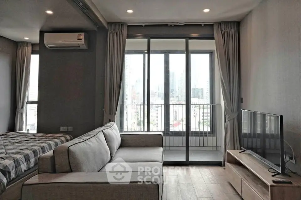 Modern living room with balcony and city view, featuring sleek furniture and natural light.