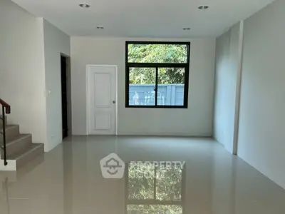 Spacious empty living room with large window and staircase, perfect for customization.