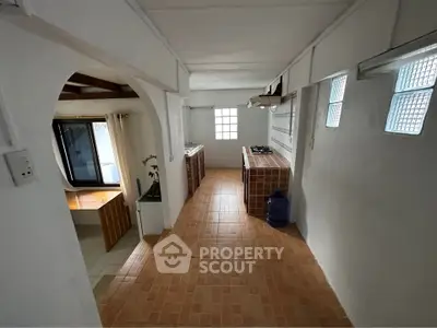 Spacious kitchen with open layout and gas stove, featuring tiled flooring and ample natural light.