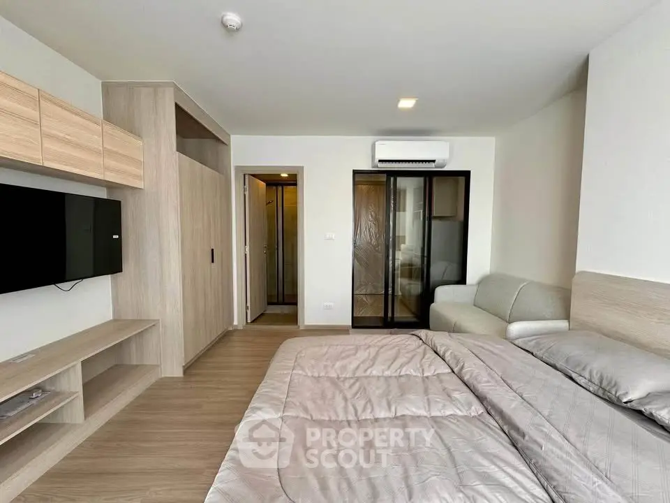 Modern bedroom with sleek design, featuring a cozy bed, wall-mounted TV, and stylish storage solutions.
