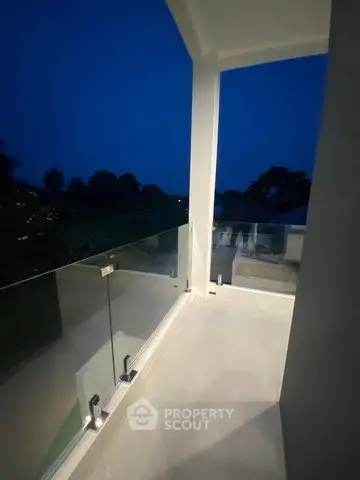 Elegant balcony with glass railing offering serene night views in a modern home.