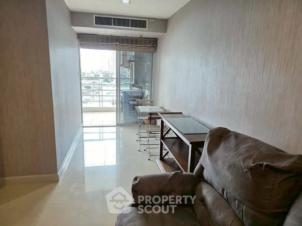 Cozy living room with balcony access and modern furnishings in a high-rise apartment.