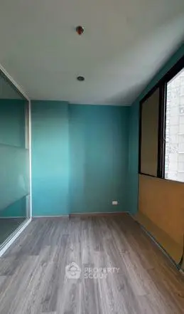 Spacious room with large windows and modern flooring, perfect for a home office or study area.