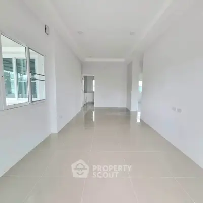 Spacious empty room with tiled flooring and large window, perfect for customization.