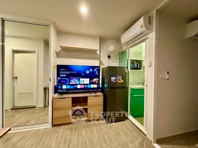 Modern living room with smart TV, air conditioning, and sleek kitchen access.