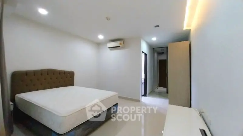 Spacious bedroom with modern design and ample natural light, featuring a comfortable bed and sleek furnishings.