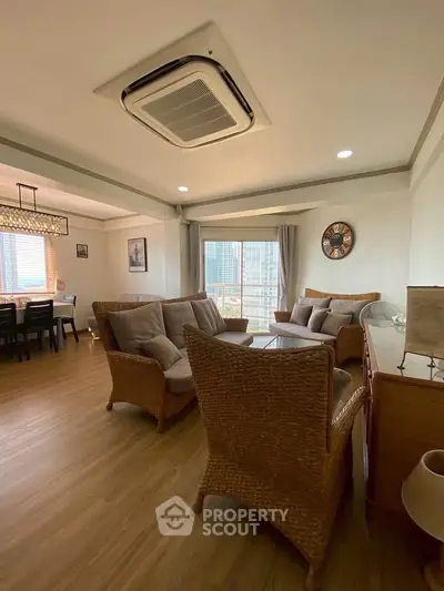 Spacious living room with elegant wicker furniture and dining area, perfect for modern living.