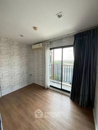 Spacious room with modern brick walls and balcony view, perfect for urban living.