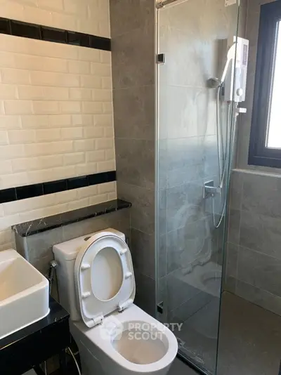 Modern bathroom with glass shower and sleek fixtures in contemporary apartment.