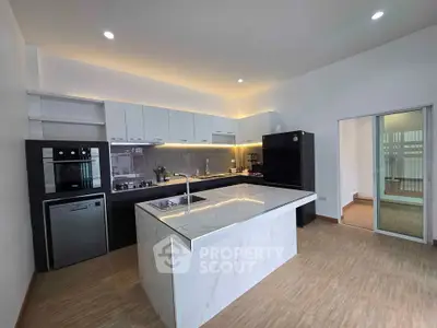 Modern kitchen with marble island and sleek appliances in open layout design.