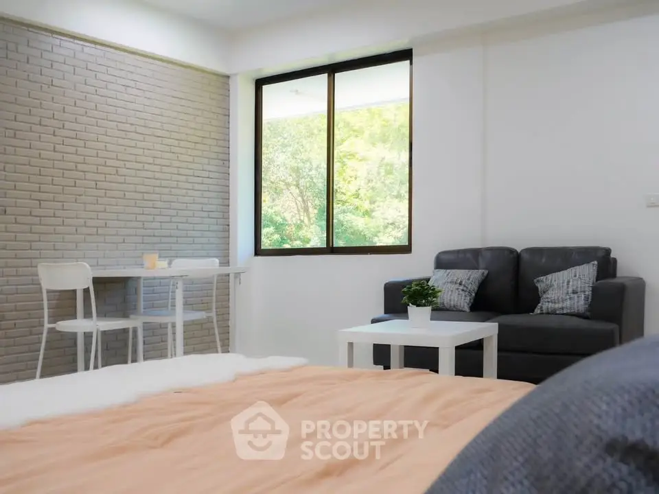 Cozy living room with modern decor and large window offering a serene garden view.