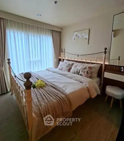 Cozy bedroom with elegant decor and natural light through large window.