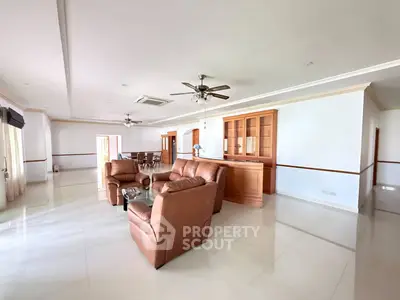 Spacious living room with elegant leather sofas and ceiling fans in a modern open-plan layout.