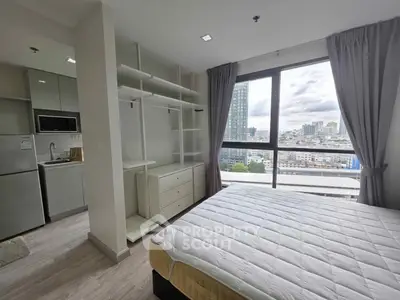 Modern bedroom with city view, featuring built-in storage and sleek kitchen appliances.