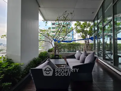Spacious balcony with modern seating and lush greenery offering city views.