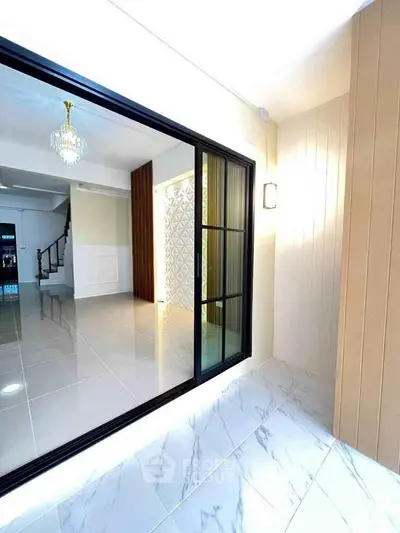 Elegant modern interior with sliding glass doors and chandelier, showcasing a spacious and stylish living area.