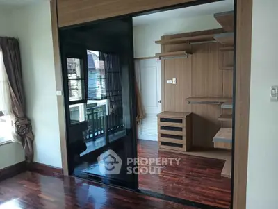 Spacious bedroom with elegant wooden flooring and built-in wardrobe in modern apartment.