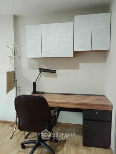 Modern study room with sleek desk, chair, and wall cabinets in a stylish home office setup.