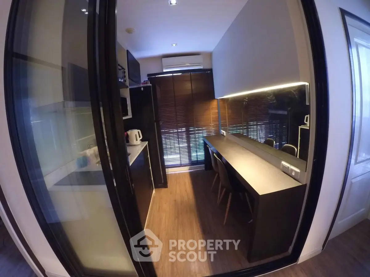 Modern kitchen with sleek design, featuring dark cabinetry and a long dining counter under ambient lighting.