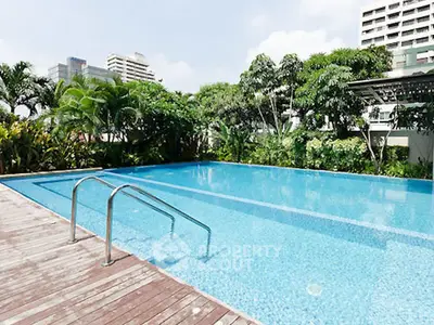 Luxurious residential pool with lush greenery and city skyline views.