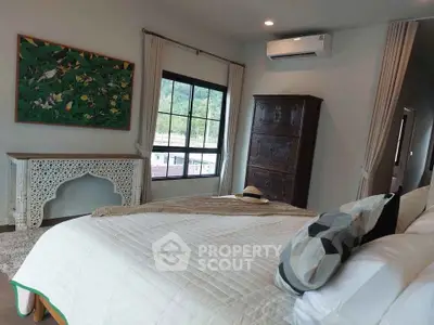Spacious bedroom with elegant decor and large window offering scenic views, perfect for relaxation and comfort.