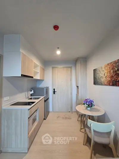 Modern kitchen with sleek cabinetry and cozy dining area in a stylish apartment.