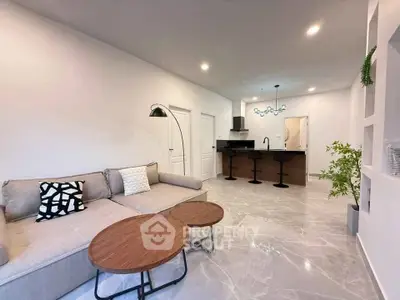 Modern living room with sleek design and open kitchen layout, featuring stylish furniture and elegant lighting.