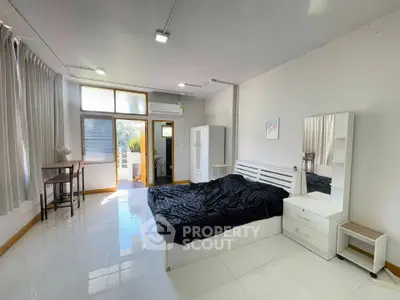 Spacious bedroom with modern furnishings and natural light, featuring a small balcony for added charm.