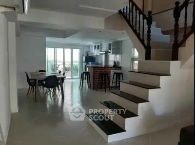 Spacious open-plan kitchen and dining area with modern staircase and natural light.