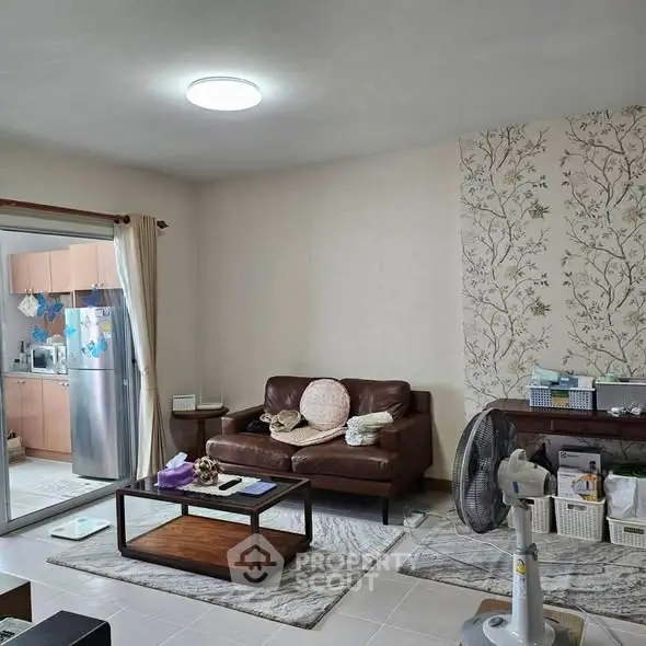 Cozy living room with leather sofa and open kitchen view, perfect for modern living.