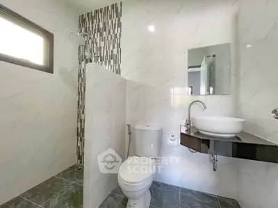Modern bathroom with sleek design, featuring a shower, toilet, and stylish sink area.