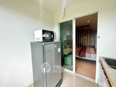 Modern kitchen with fridge and microwave adjacent to cozy bedroom